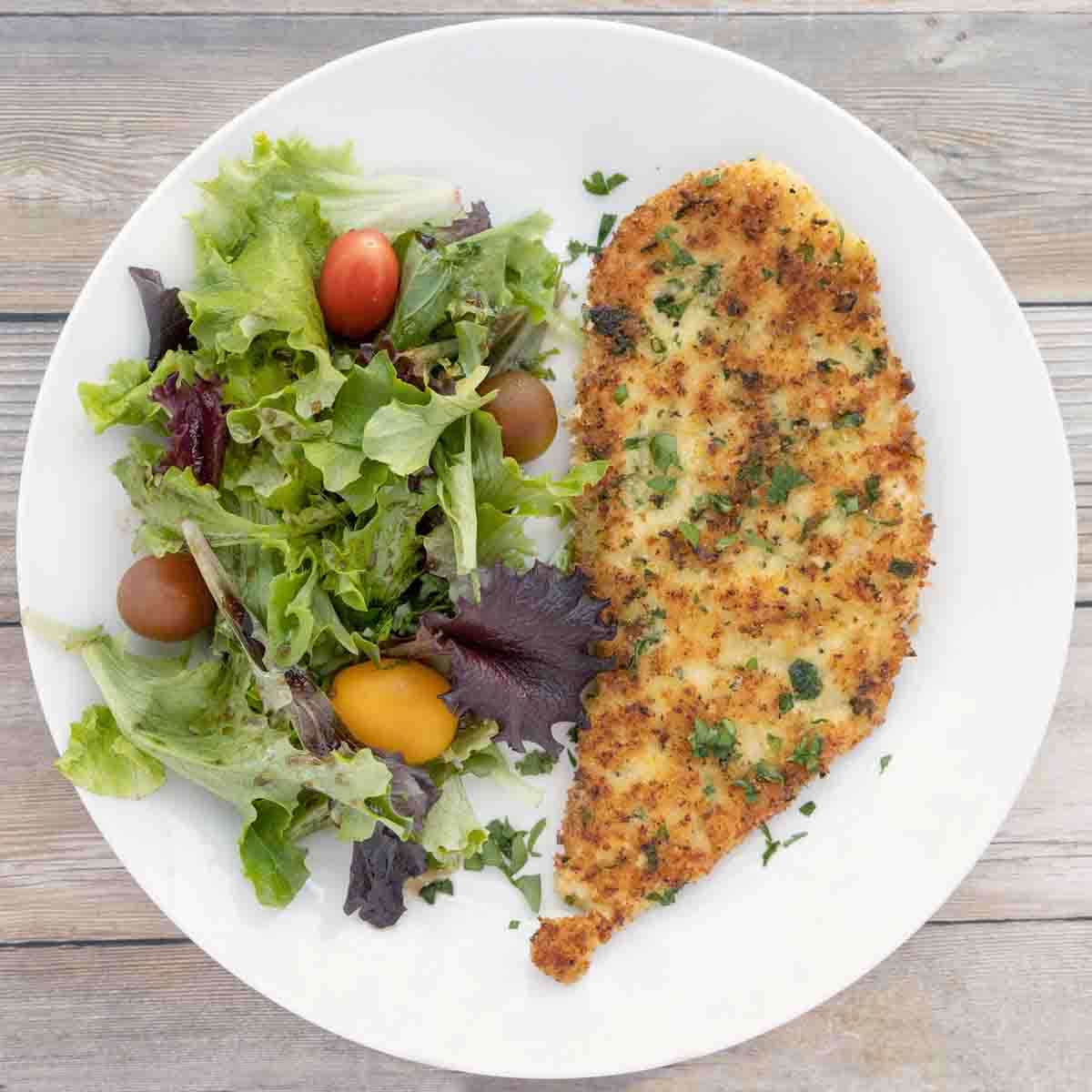 Chicken Milanese with salad on a white plate