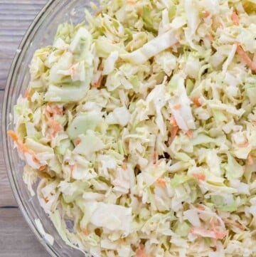 shredded cabbage mixed with coleslaw dressing in a glass bowl.