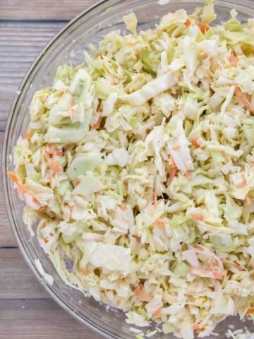 shredded cabbage mixed with coleslaw dressing in a glass bowl.