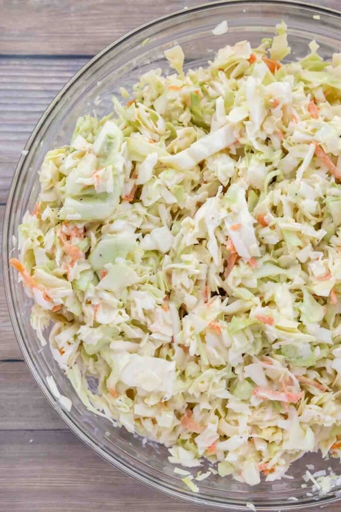shredded cabbage mixed with coleslaw dressing in a glass bowl.