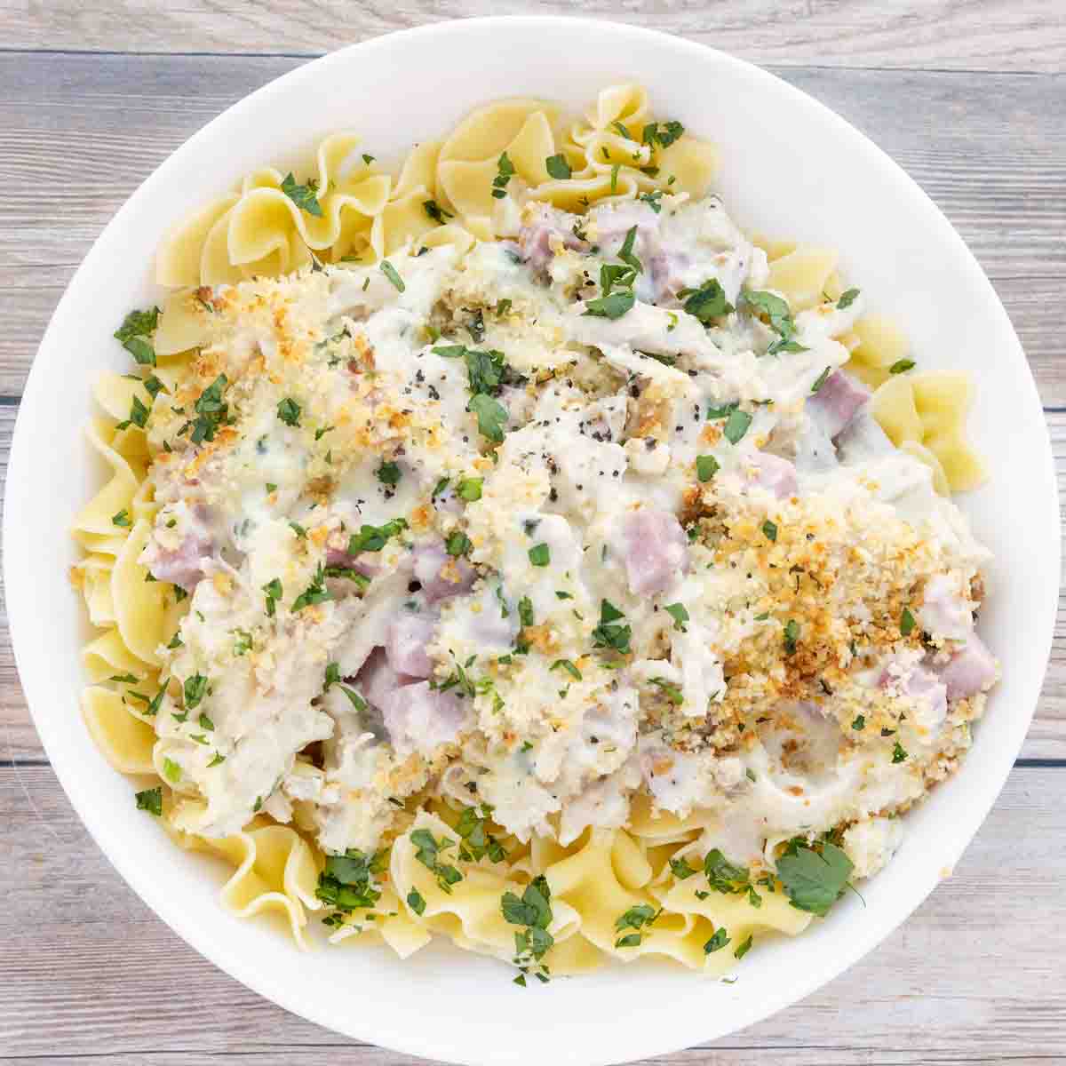 chicken cordon bleu casserole over egg noodles in a white bowl