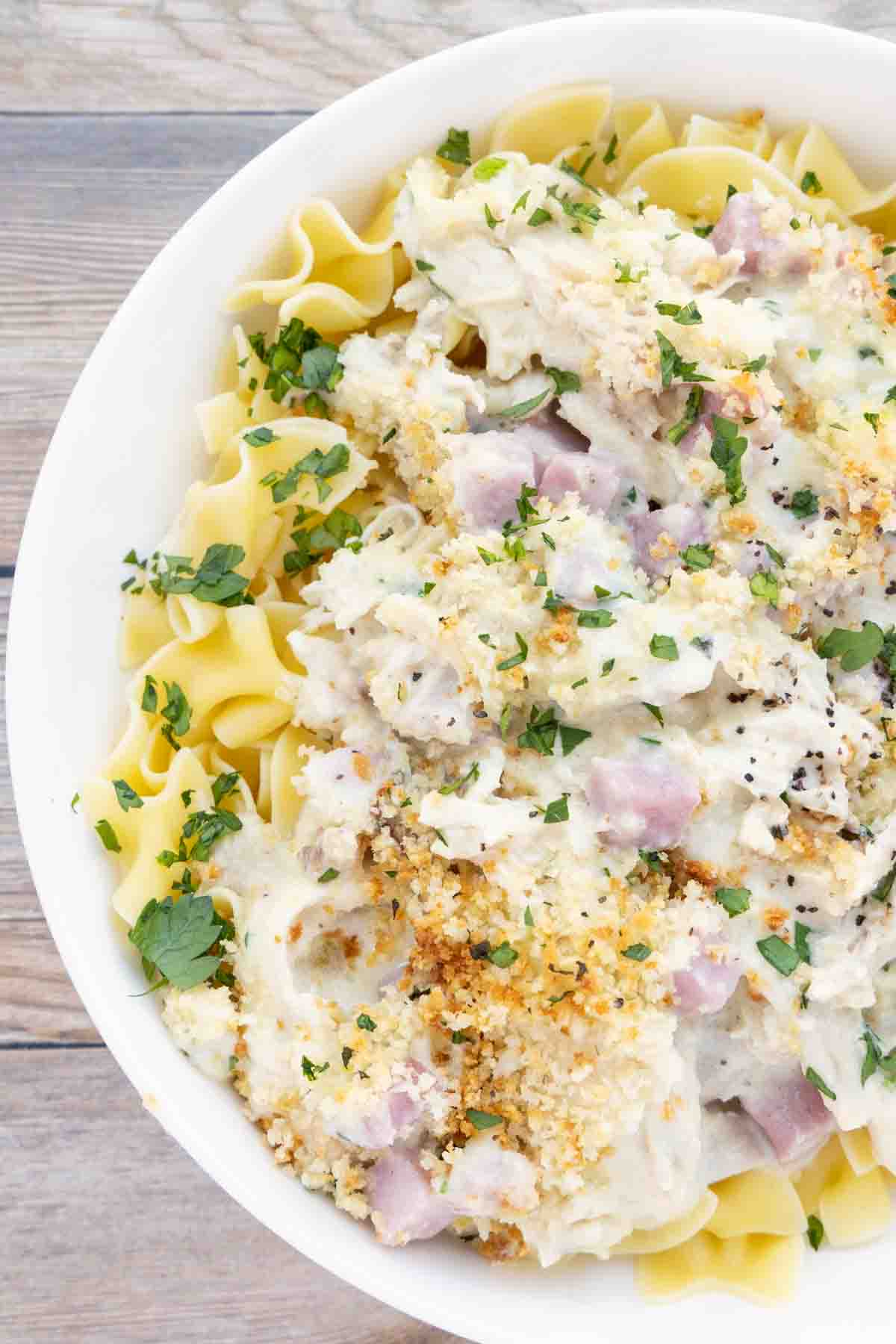 chicken cordon bleu casserole over egg noodles in a white bowl