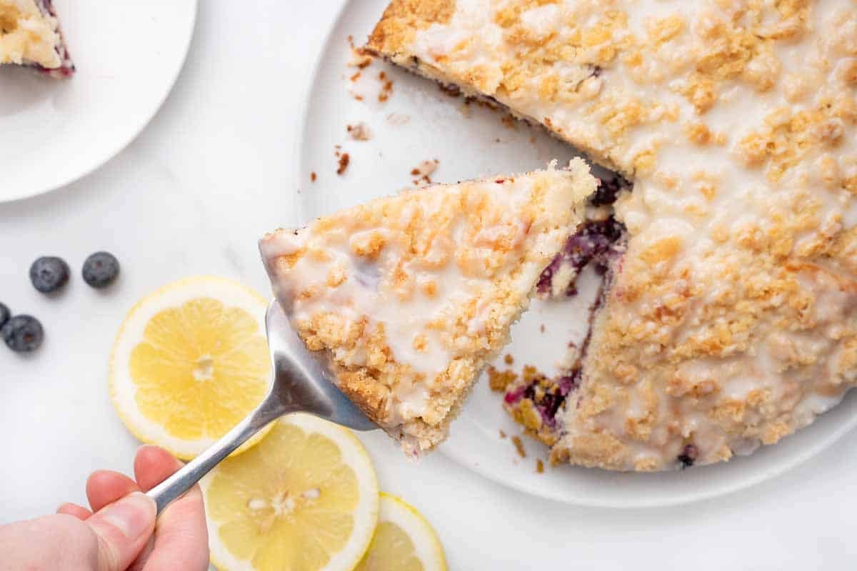 slice of blueberry coffee cake being taken out of whole cake