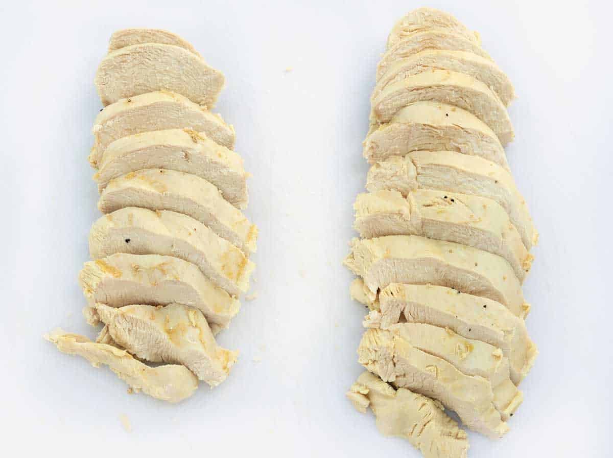 sliced poached chicken breast on white cutting board