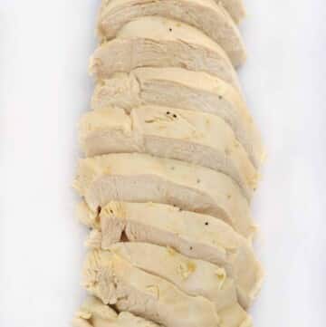 sliced poached chicken breast on white cutting board