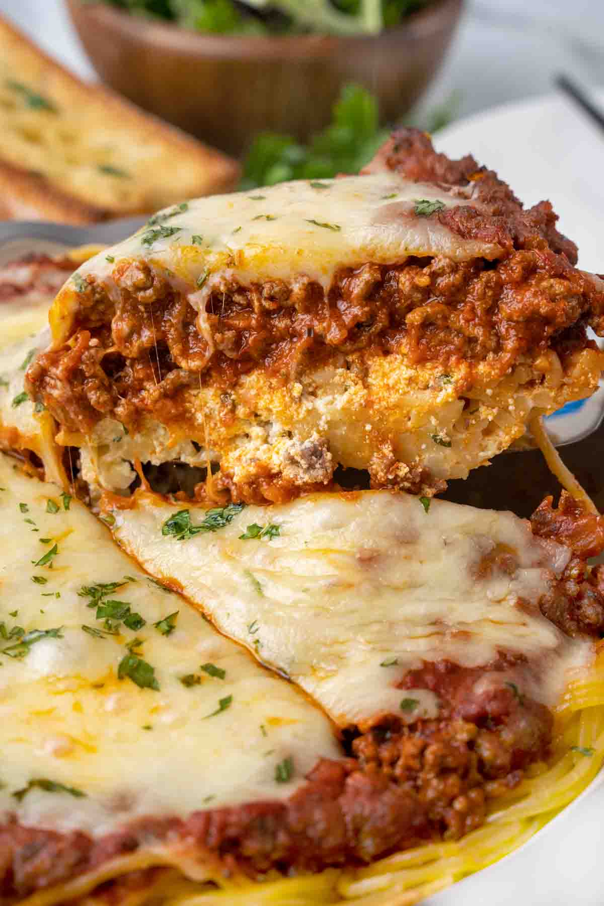 Slice of spaghetti pie on a spatula being taken out of the whole pie.