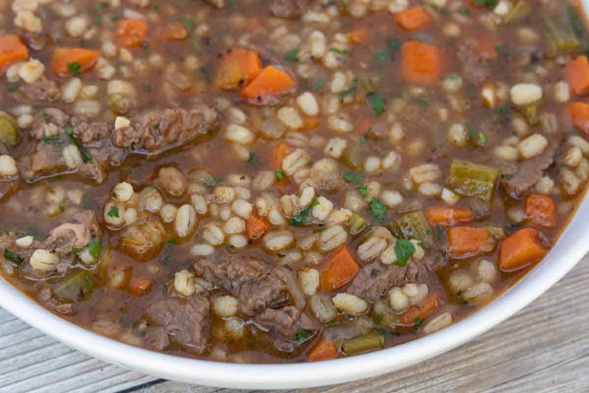 Beef barley soup in white bowl.