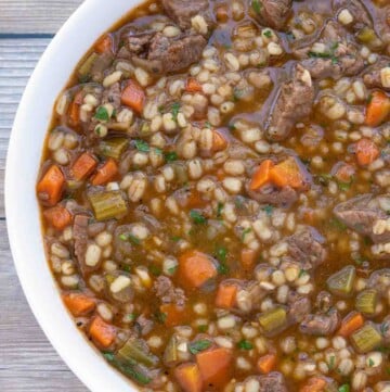 Beef barley soup in white bowl.