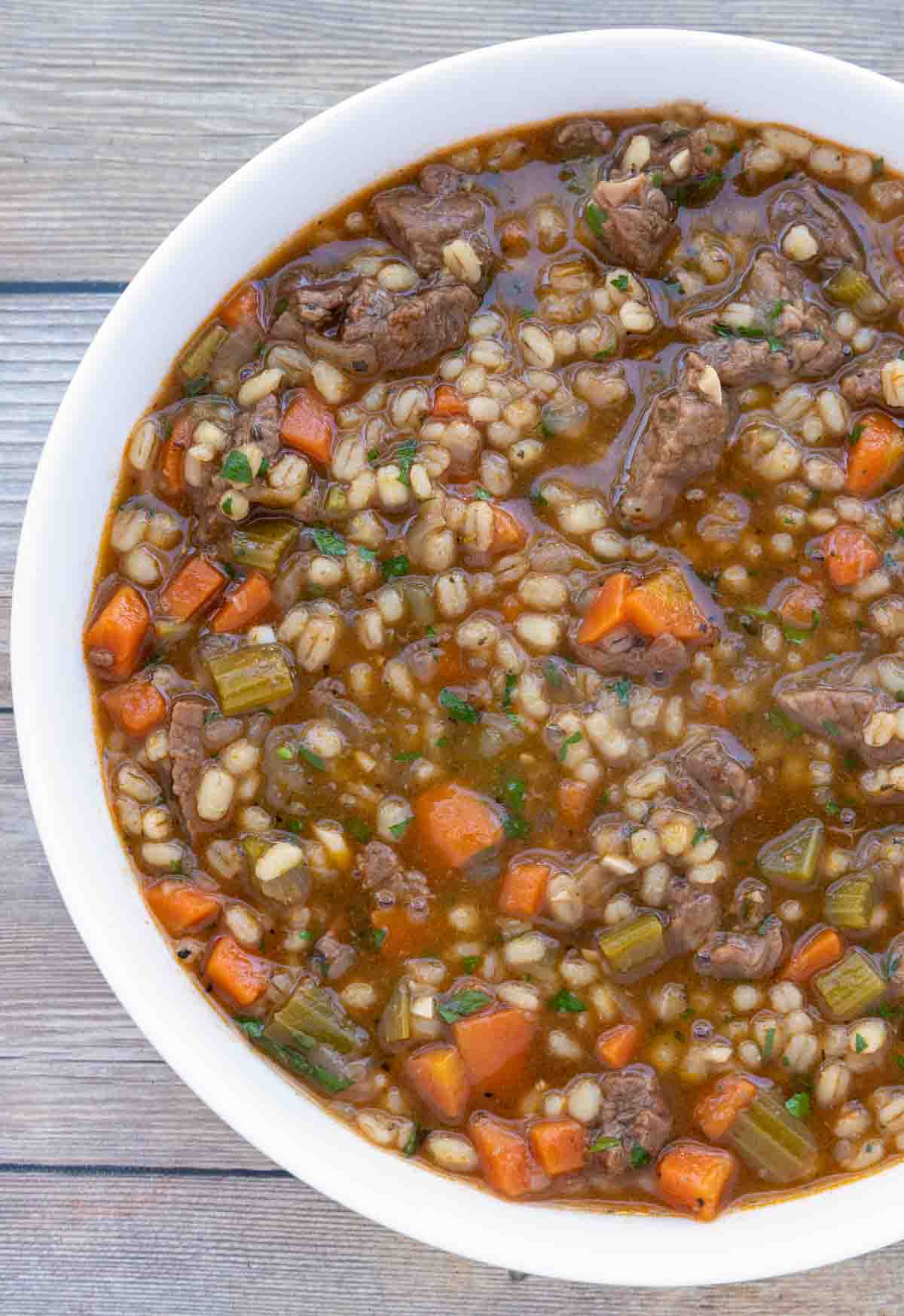 Beef barley soup in white bowl.