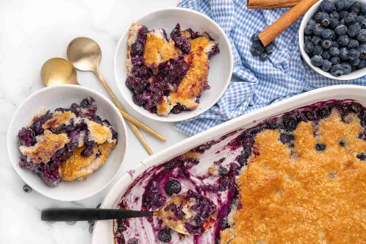 pan of blueberry cobbler with 2 dishes of the dessert.