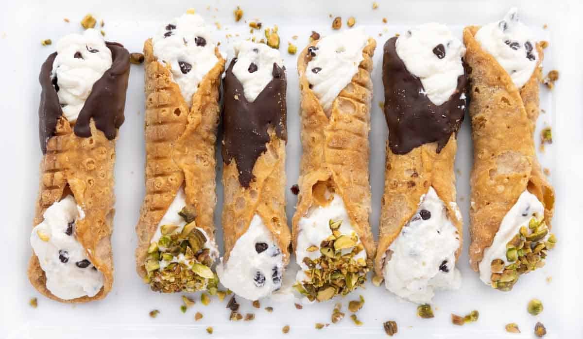 six cannoli on a white platter.