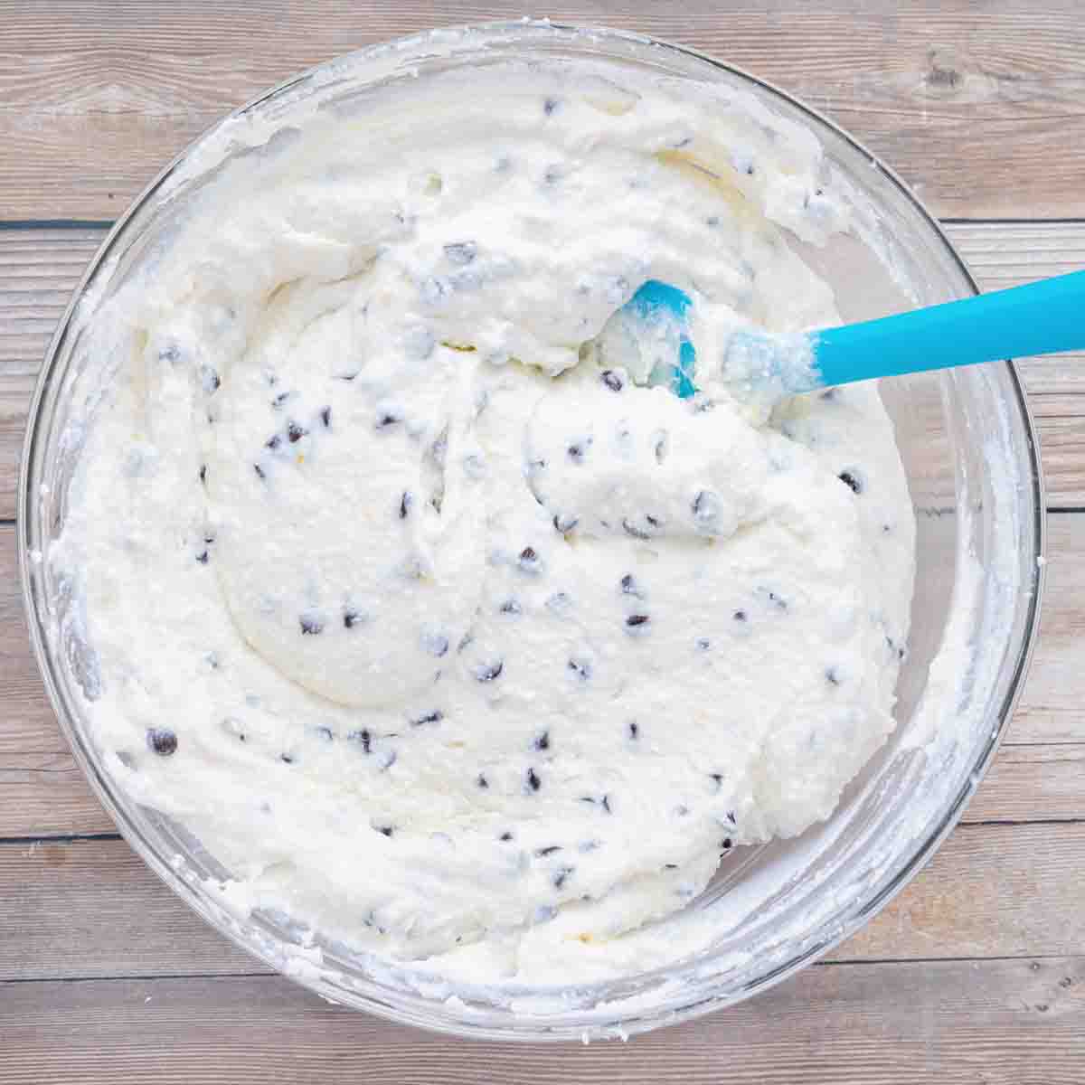 cannoli cream in glass bowl with blue silicone spatula.