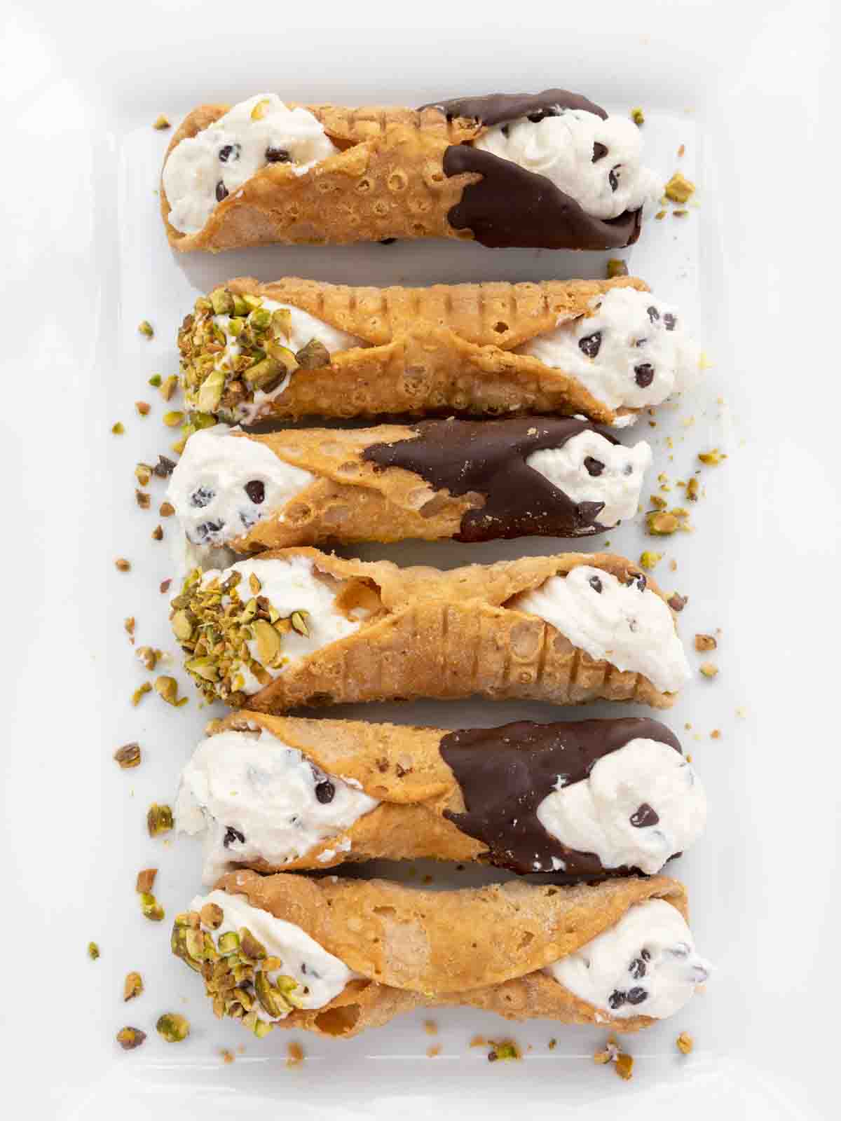 six cannoli on a white platter..