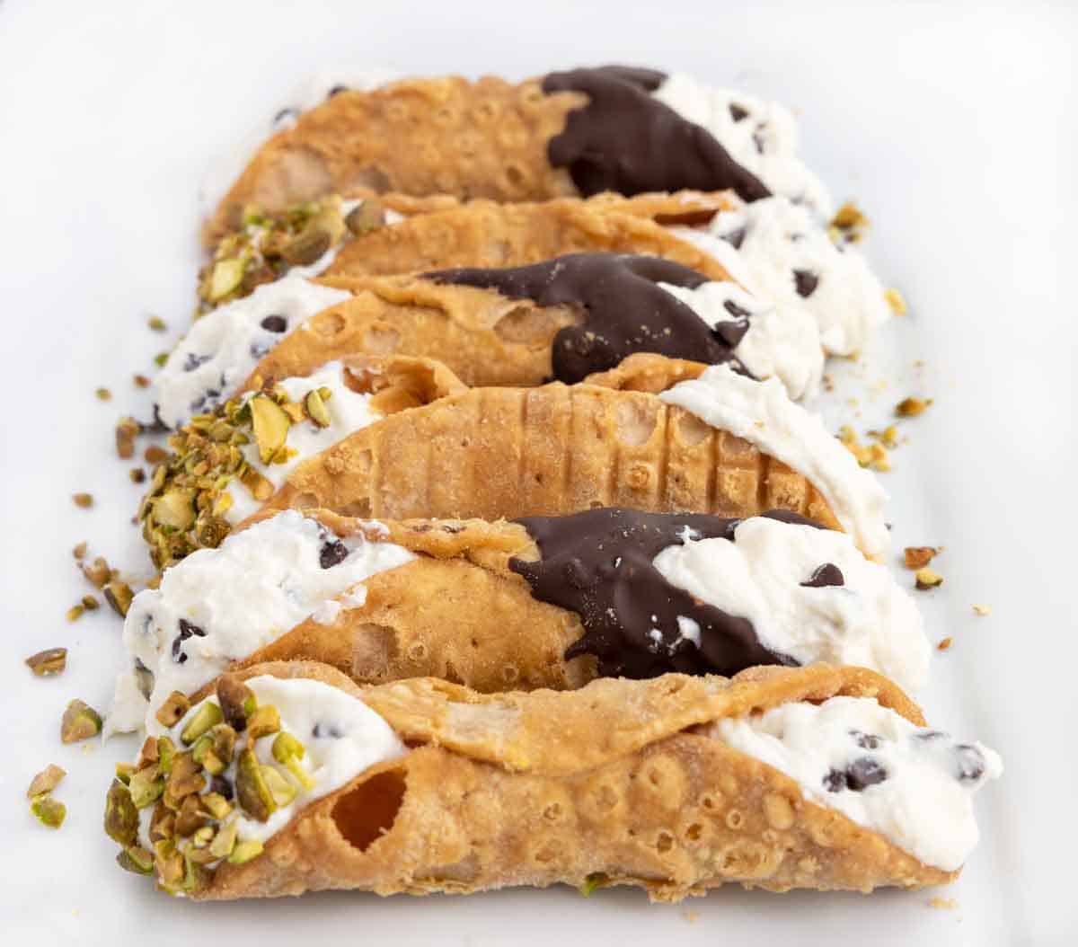side view of cannoli on white platter.