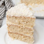 three layer coconut cake slice on a white plate.