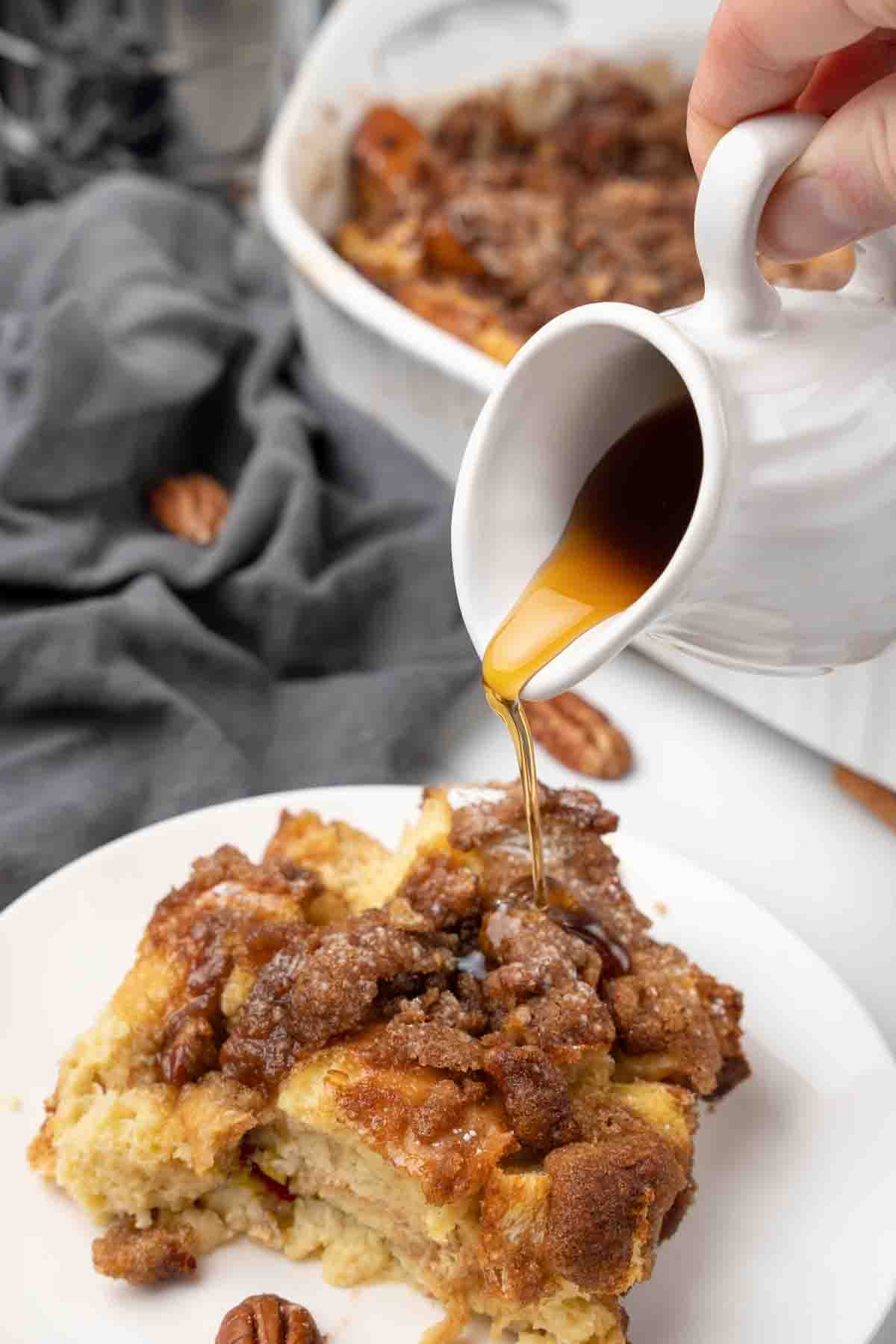 syrup being poured on french toast casserole on white plate.