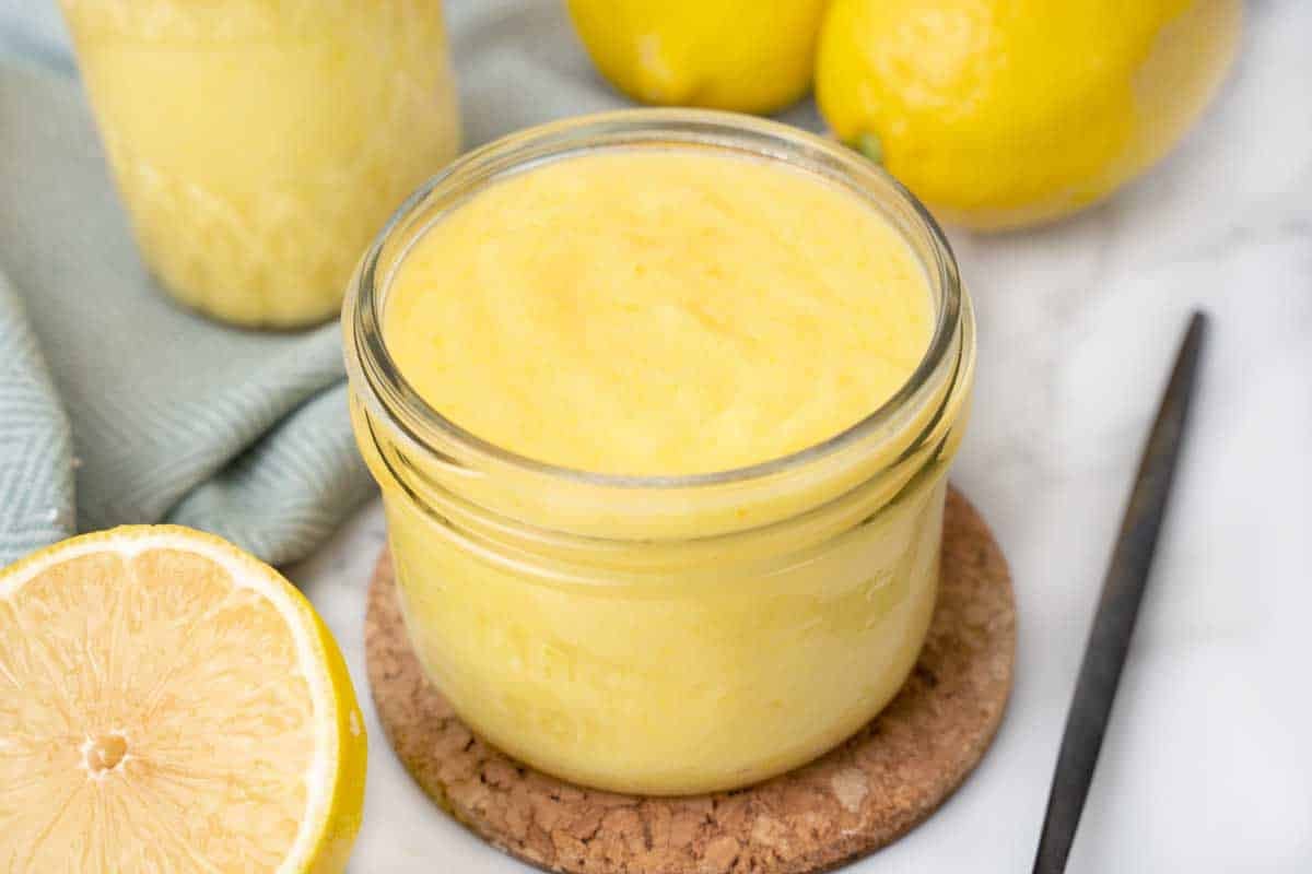 jar of lemon curd on a brown coaster.