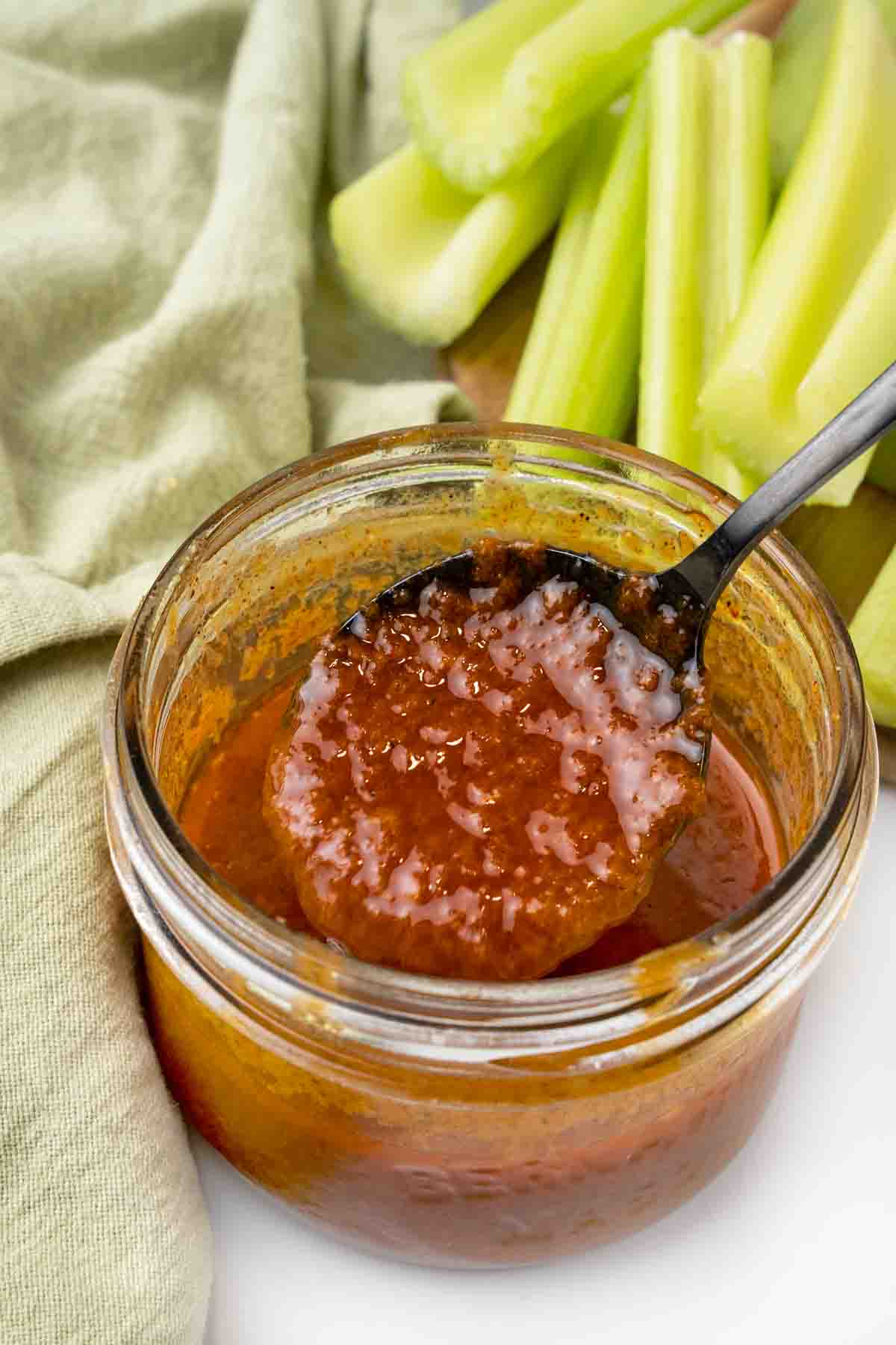 Nashville hot sauce in a glass jar with a black spoon.