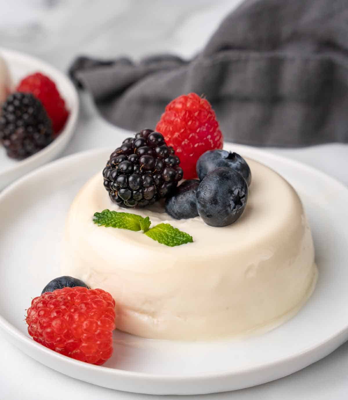 Panna cotta on white plate with berries.