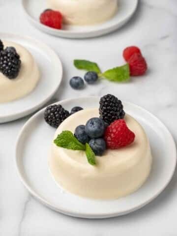 Panna cotta on white plate with berries.