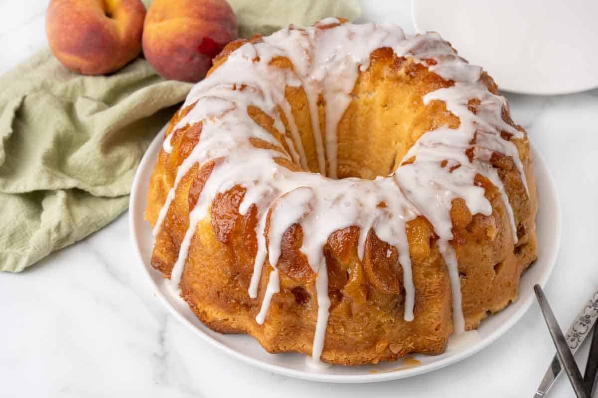 Whole glazed peach cobbler pound cake on a white platter.