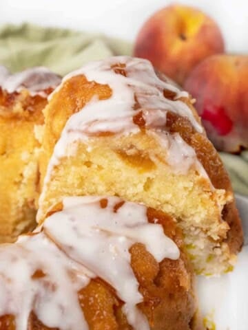 slice of peach cobbler pound cake being taken out of the whole cake.