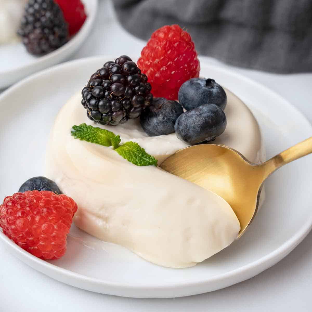 taking a spoonful out of the panna cotta with berries.