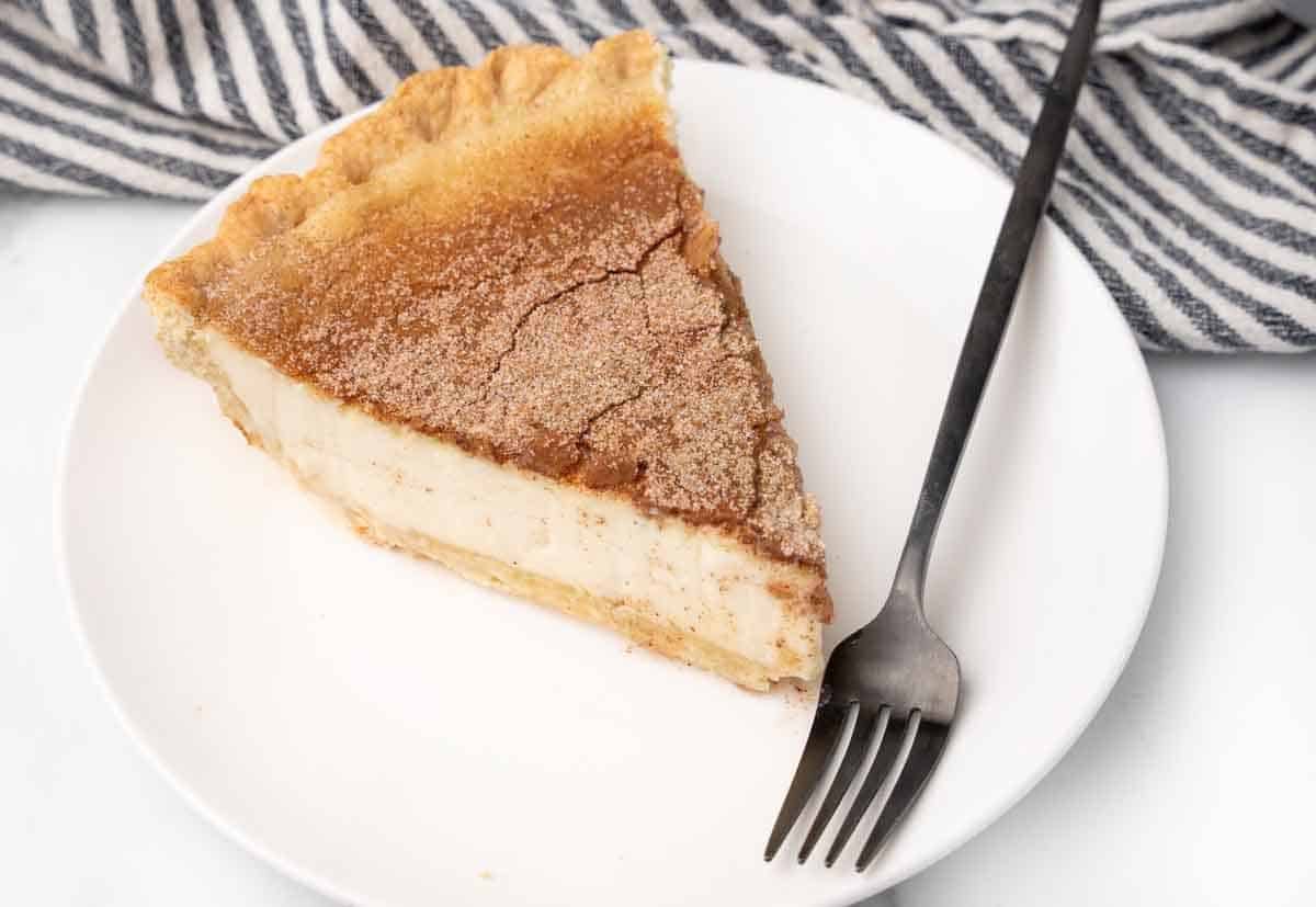 slice of sugar pie on a white plate with a fork.