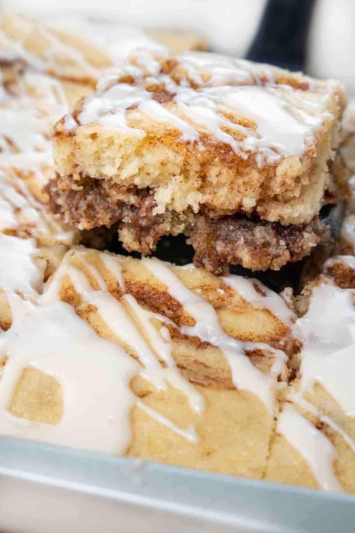 slice of cinnamon roll cake being taken out of pan.