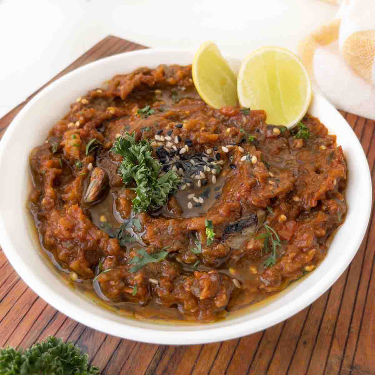 roasted eggplant dip in a white bowl with lemons.