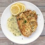 flounder francaise with lemon butter sauce and lemon circles on a white plate