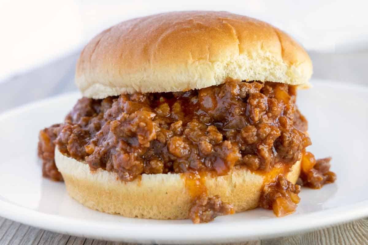 sloppy joes on bun on a white plate.