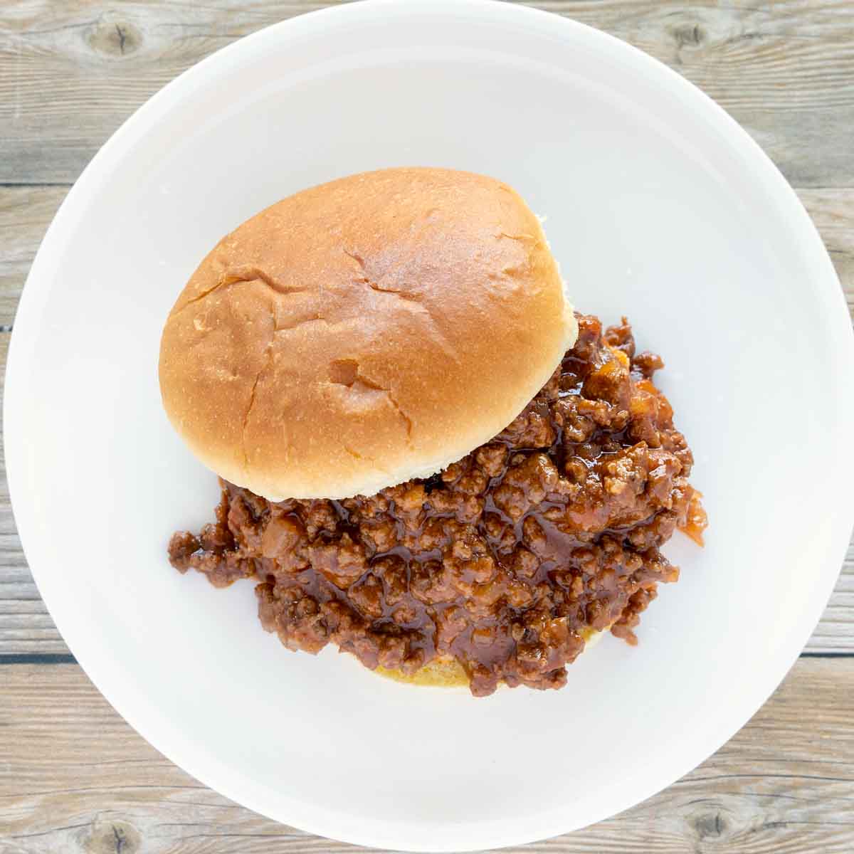 sloppy joes on bun on a white plate.