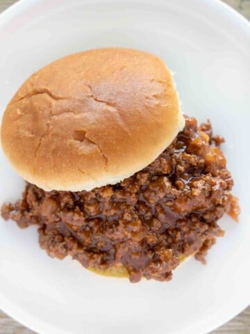 sloppy joes on bun on a white plate.