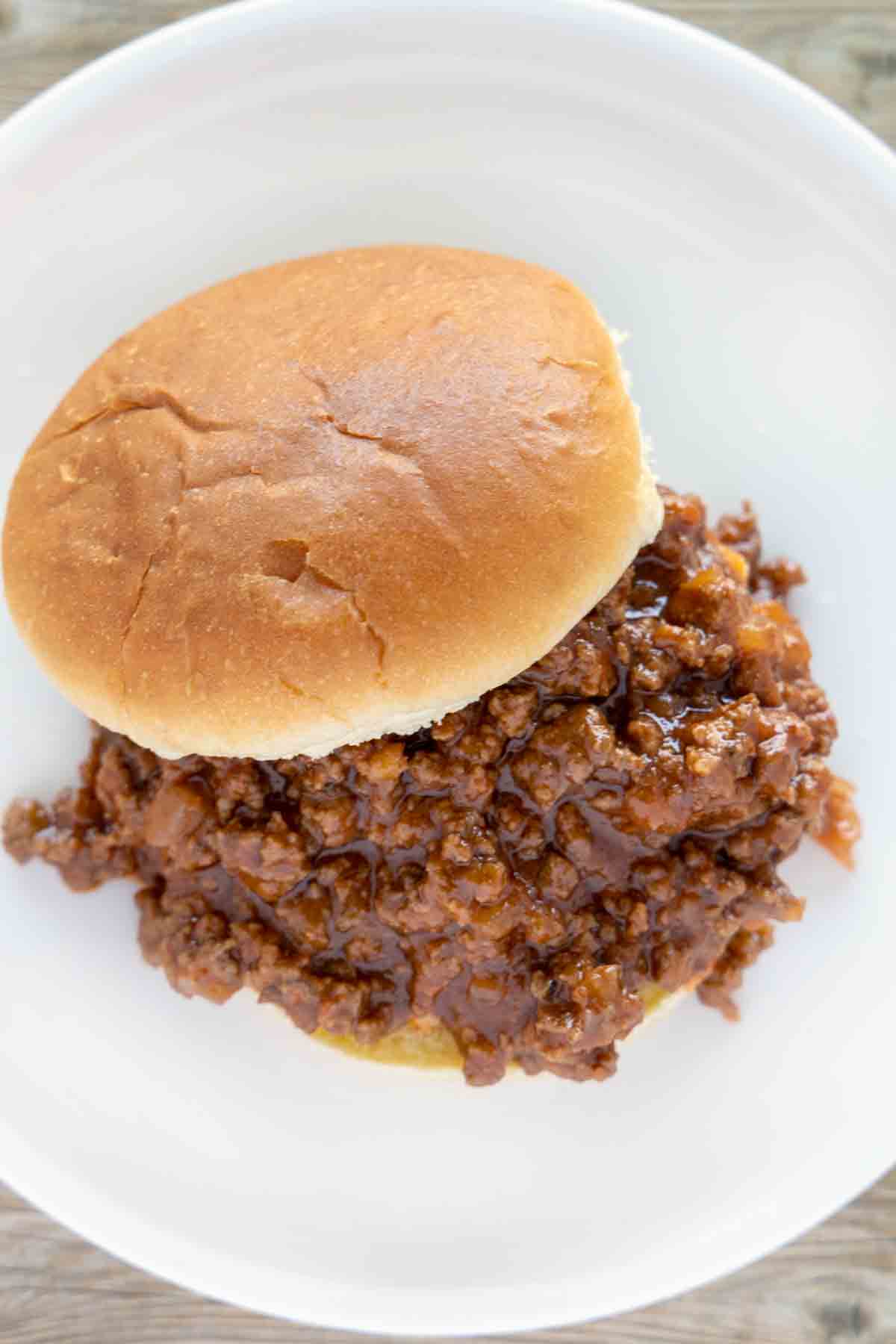 sloppy joes on bun on a white plate.