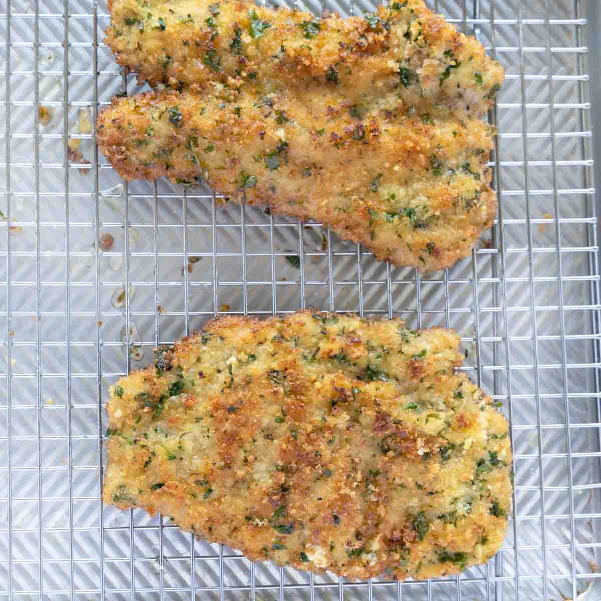 cooked veal cutlets draining on wire rack.