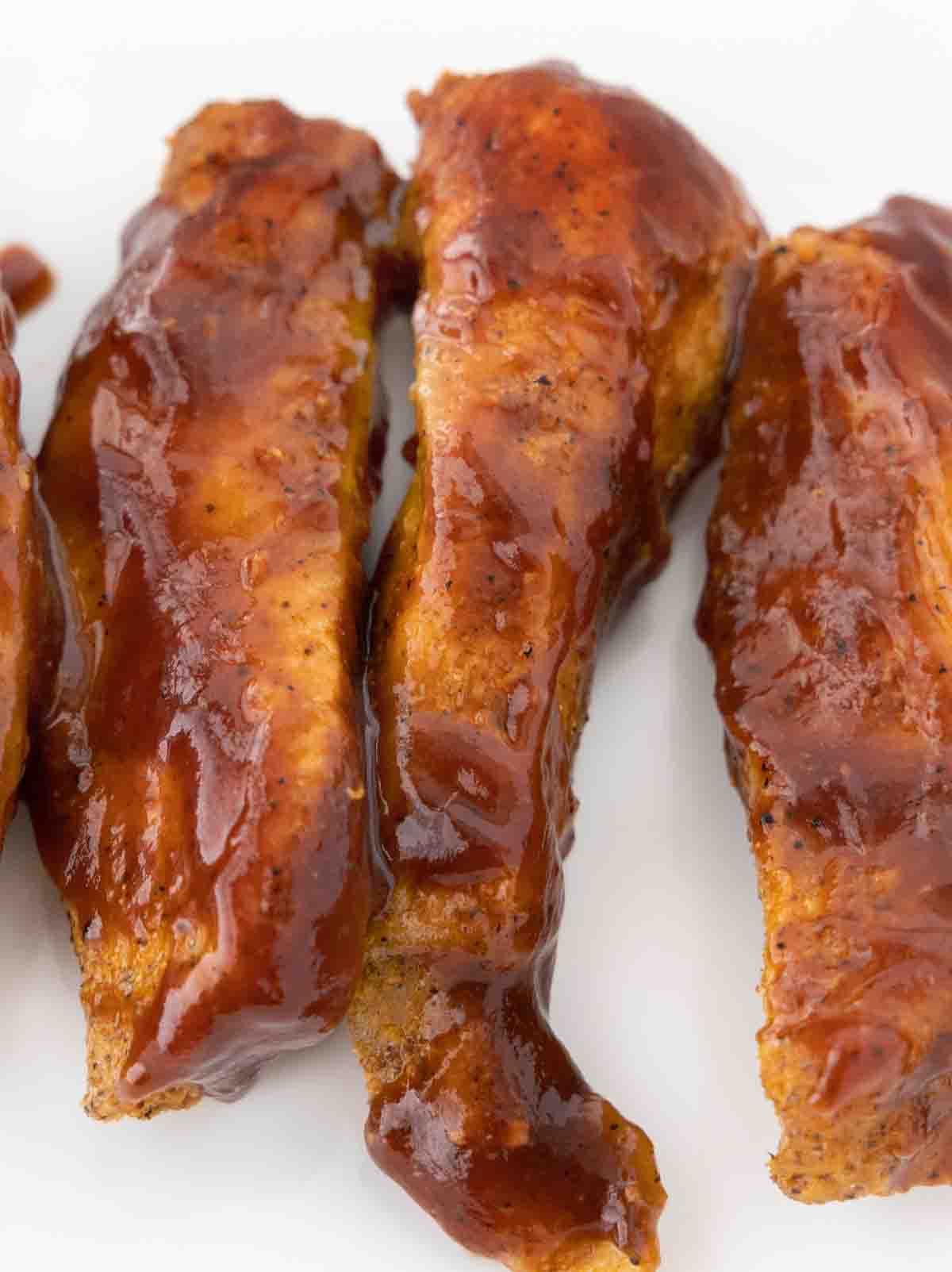 Smoked country style ribs with bbq sauce on a white platter.