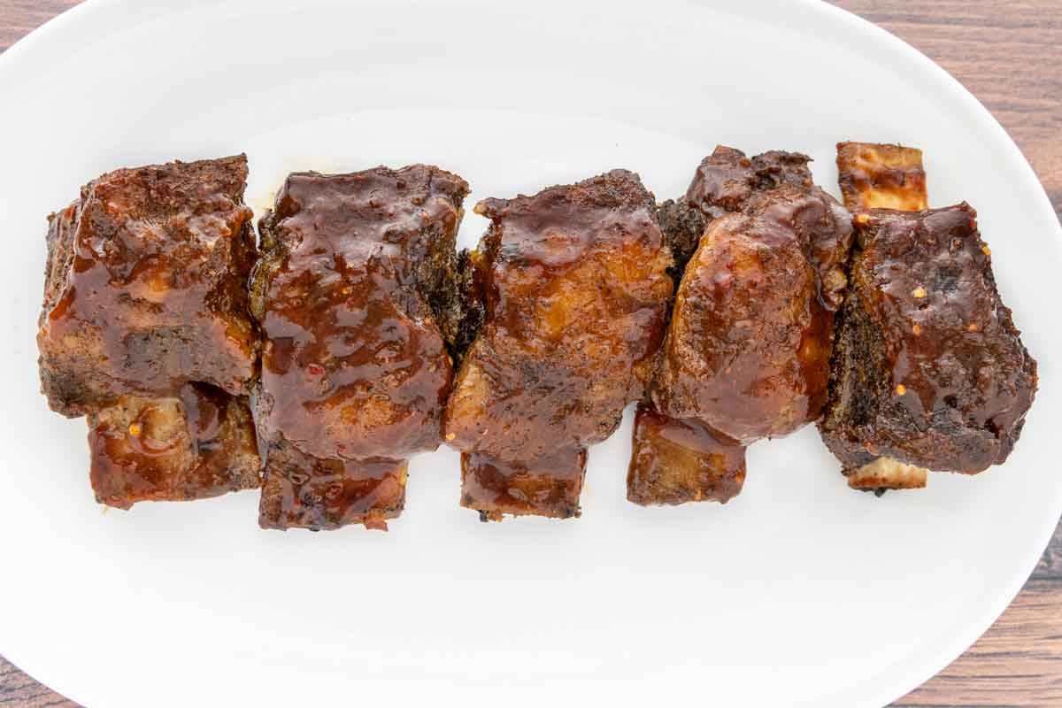 Barbecue smoked beef short ribs on a white platter.
