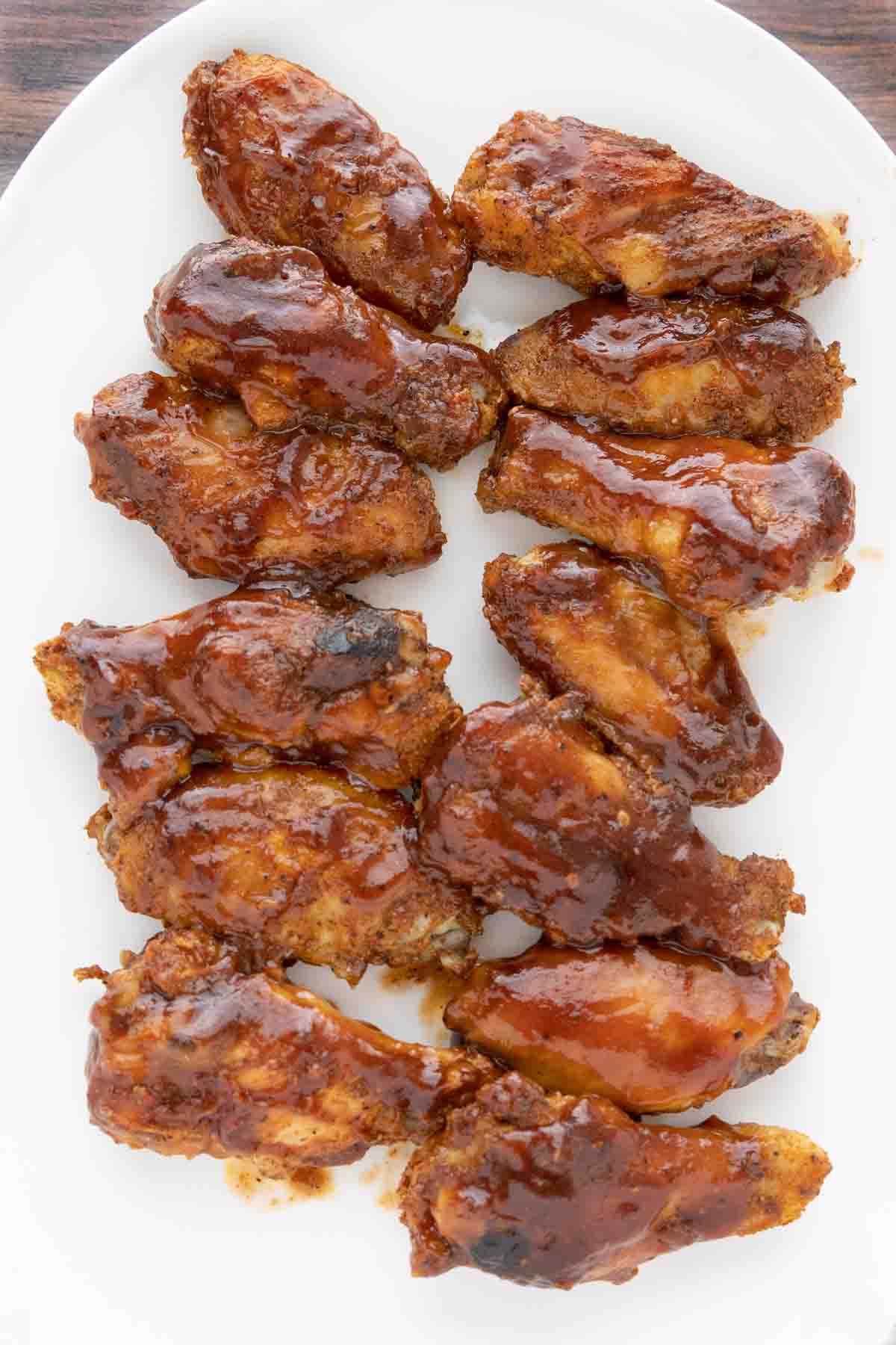 Wings with barbecue sauce on a white platter.