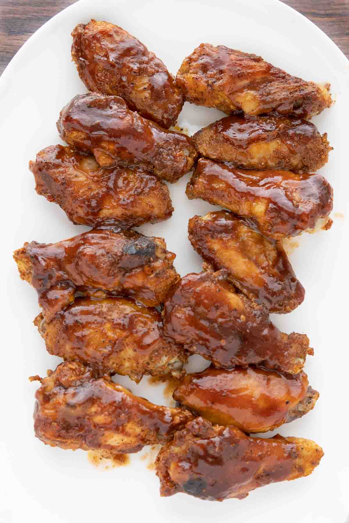 smoked chicken wings with barbecue sauce on a white platter.