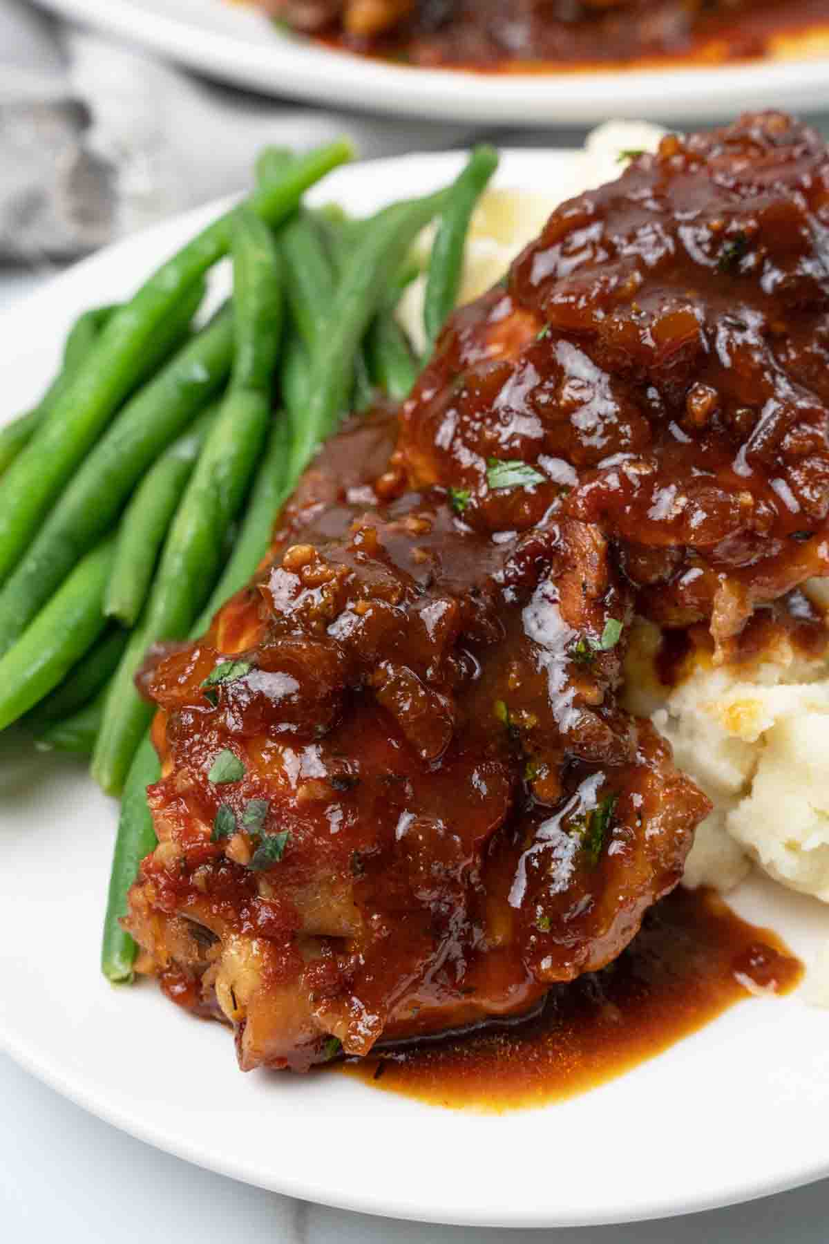 slow cooker chicken thighs on plate with green beans.