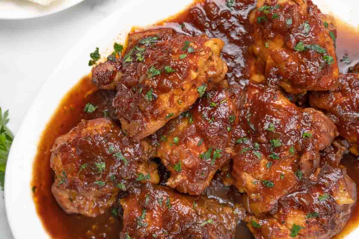 slow cooker chicken thighs on white platter.