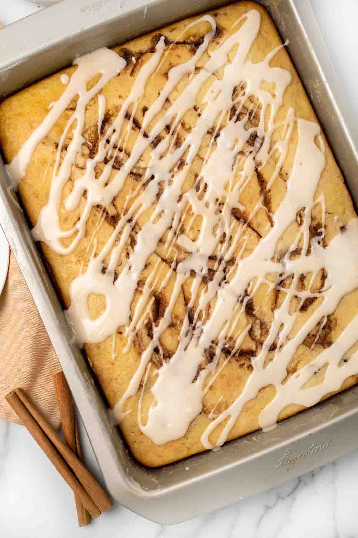 cinnamon roll cake with vanilla glaze in the pan.