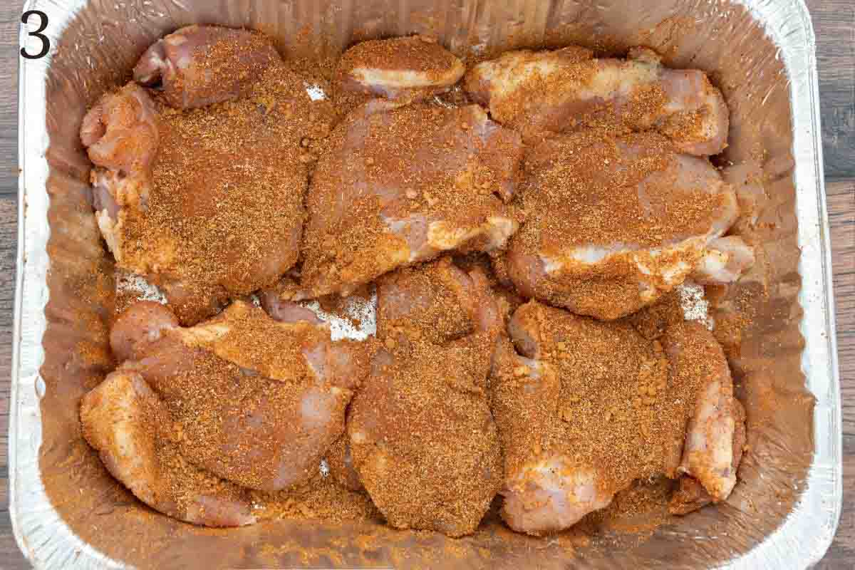 seasoned raw chicken thighs in a foil pan.
