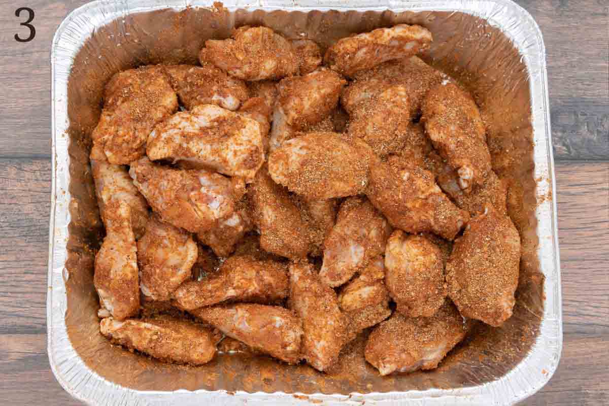 Chicken wings with seasoning in an aluminum pan.