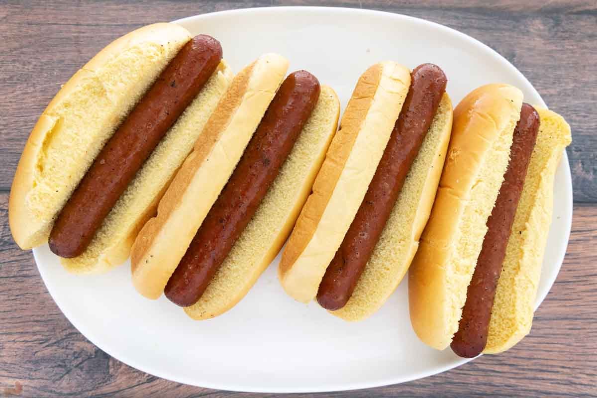 Smoked hot dogs on a white platter.