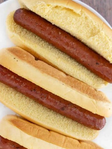 Smoked hot dogs on a white platter.