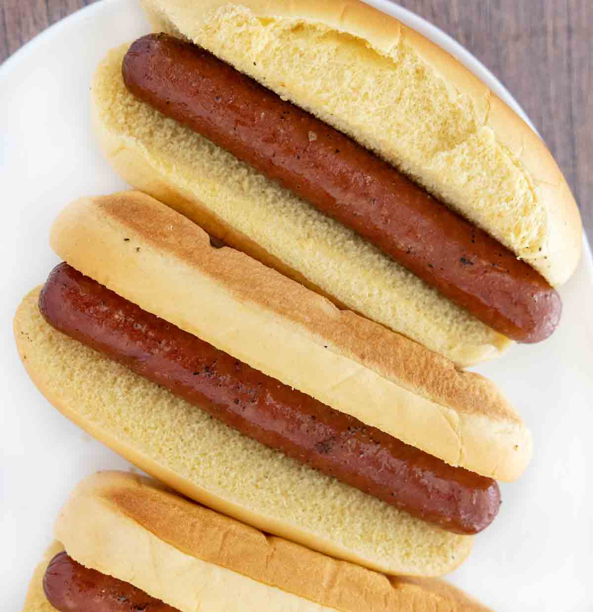 Smoked hot dogs on a white platter.