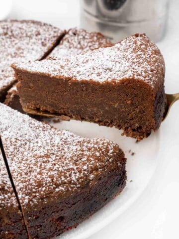 slice of torta caprese being taken out of the whole cake.