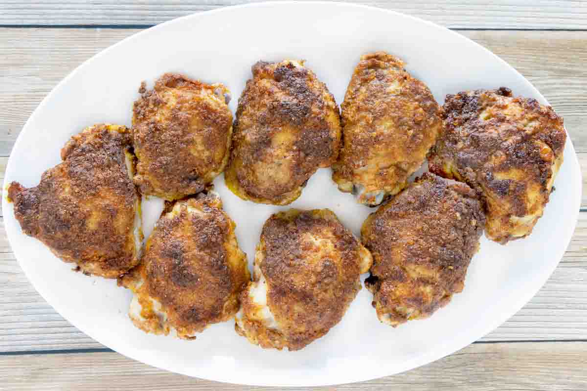 Baked chicken thighs on a white platter.